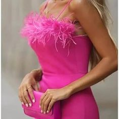 a woman in a bright pink dress holding a pink purse and posing for the camera