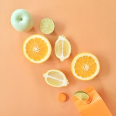 oranges, limes and an apple sitting on a table next to each other