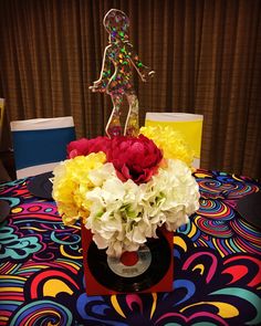 a vase with flowers on top of a colorful table cloth at a party or event