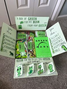 an open green box filled with candy sitting on the floor next to a white door