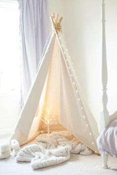 a white teepee with lights on it in a bedroom