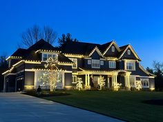 a large house with christmas lights on it's windows and trees in the front yard