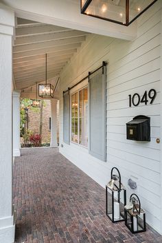 a brick walkway leading to a house with two mailboxes on each side and a lantern hanging from the ceiling