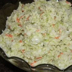 a glass bowl filled with coleslaw and carrots on top of a table