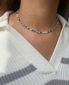 a woman wearing a blue and white beaded necklace with a silver clasp on her neck