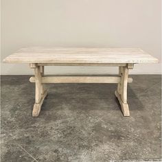 a wooden table sitting on top of a cement floor in front of a white wall