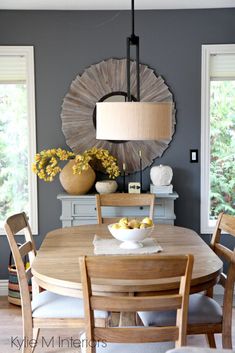 a dining room table with chairs and a bowl of fruit on top of the table