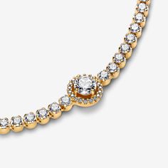 Level up your outfit with the Sparkling Halo Tennis Bracelet. Finished in elegant 14k gold plating, this hand-finished piece is decorated with sparkling stones. The centerpiece features a big central stone surrounded by a halo of clear cubic zirconia. There’s a small stone detail at the end of the chain for added sparkle. This tennis bracelet includes a lobster clasp for safe closure. Style with other shimmering Pandora Timeless pieces for a classic look that stands out. - Pandora Sparkling Halo Tennis Bracelet - 14k Gold-plated unique metal blend / Cubic Zirconia / Clear - Sz. 7.1 in Elegant Bracelet With Sparkling Stones, Classic Gold Sparkling Bracelets, Classic Yellow Gold Tennis Bracelet With Sparkling Stones, Elegant Gold Bracelets With Sparkling Stones, Classic Yellow Gold Diamond Bracelet With Sparkling Stones, Elegant Gold Bracelet With Sparkling Cubic Zirconia Stones, Elegant Gold Bracelet With Sparkling Stones, Elegant Gold Bracelets With Brilliant Cut, Elegant Gold Bracelet With Brilliant Cut