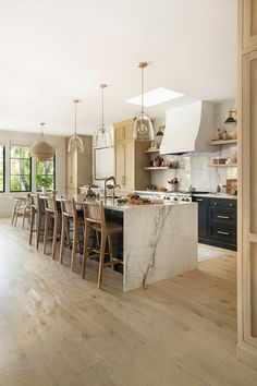 a large kitchen with an island and marble counter tops in the center is surrounded by wooden flooring