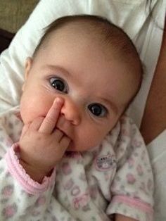 a baby laying on top of a woman's stomach holding her hand up to her mouth