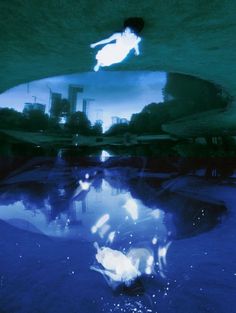 the reflection of a person on a surfboard is seen in the water under an underwater pool