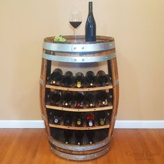 a wine rack with several bottles and glasses on it in the middle of a wooden floor