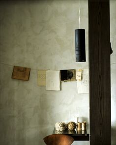 a chair and table in a room with papers hanging on the wall above it, next to a lamp