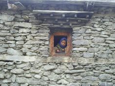 a small child is looking out the window of a stone building with rocks on it