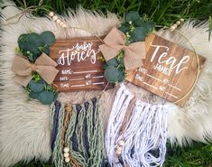 two wooden signs with greenery on them sitting in the grass next to each other