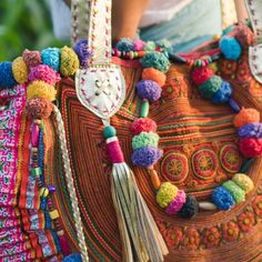 a colorful handbag with tassels and beads on the handle is being held by a woman