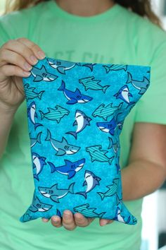 a woman holding up a blue pillow with sharks on it