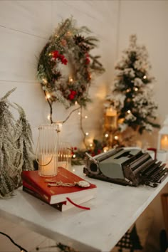 an old typewriter sitting on top of a table next to christmas trees and wreaths