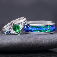 two rings with blue and green stones on top of each other, sitting on a rock