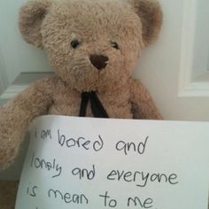 a teddy bear holding a sign that says i am bored and lonely and everyone is mean to me