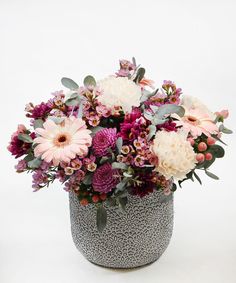 a vase filled with lots of purple and white flowers