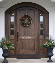 two planters with wreaths on the front door