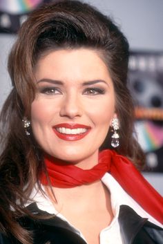 a woman with long hair wearing a red scarf around her neck and smiling at the camera