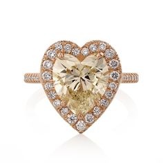 a heart shaped yellow diamond ring with diamonds around the band and an oval center stone