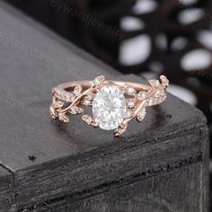 a rose gold engagement ring set with an oval diamond center and leaves on the band