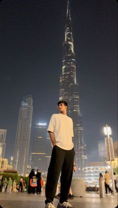 a man standing on top of a skateboard in front of a tall building at night