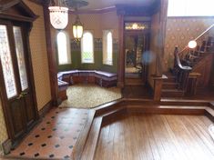 the inside of a house with wood floors and walls, stained glass windows, and wooden stairs