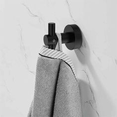 a towel hanging on the wall next to a black and white towel rack with two towels