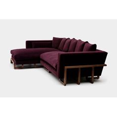 a large purple couch sitting next to a wooden table on top of a white floor