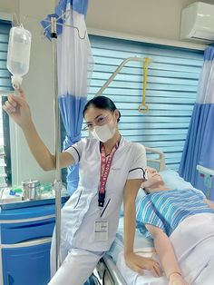 a woman in white scrubs is holding up a plastic bottle to another person on a hospital bed