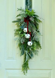 a wreath hanging on the front door of a house decorated with evergreen and white balls