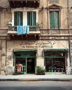 an old building with green shutters and balconies on the windows is shown