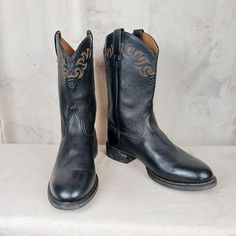 Very nice looking pair of bootscomfortable and practical. Ariat leather roper style round toe cowboy work boots. Black leather uppers and shafts with some very nice stitch work at the top of the boot. Brown leather linings and synthetic soles. Very nice condition. Some minor signs of previous wear but overall a great pair of boots with a lot of life left. Please made sure to view all the pics so you can get the best idea. Men's size 12 D (standard width) Western Moto Boots With Steel Toe, Black Country Style Boots With Round Toe, Country Style Black Round Toe Boots, Western Style Rodeo Work Boots With Round Toe, Western Work Boots For Rodeo With Round Toe, Rugged Black Work Boots For Western-themed Events, Black Rugged Work Boots For Western-themed Events, Black Reinforced Toe Work Boots For Ranch, Rugged Black Work Boots For Ranch