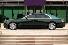 a black rolls royce parked in front of a building with steps leading up to it