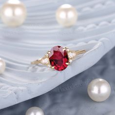 a ring with a red stone surrounded by pearls