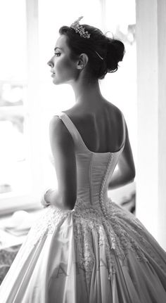 a woman in a wedding dress looking out the window