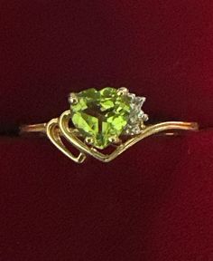 a gold ring with a green stone in the center and two diamonds on each side