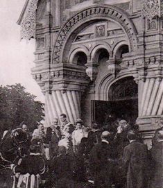 an old black and white photo of people standing in front of a building with horses