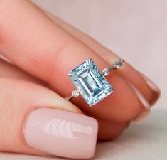 a woman's hand holding a ring with an aqua blue topazte on it