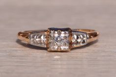 The 83rd Street: Retro Era Diamond Promise Ring. The ring features a central round diamond in a diamond-cut square mystery box topped with rhodium. On either side of the center is a tapered diamond-cut design also topped with rhodium. The ring is finished with retro-era piercing in the through-finger view. The ring is crafted in 14 karat yellow gold and is currently a finger size 6.5 yet can be adjusted to any finger size for an additional charge on request. Love this piece, but don't have the m Luxury Ring With Square Cut Single Diamond, Luxury Square Cut Single Diamond Ring, White Gold Square Cut Diamond Ring With Single Diamond, Square Cut Single Diamond White Gold Ring, Formal Square-cut Solitaire Diamond Ring, Formal Square Cut Solitaire Diamond Ring, Gift Square Cut Single Diamond Ring, Square Cut Single Diamond Ring Gift, Square Cut Single Diamond Promise Ring