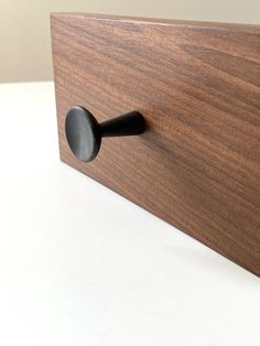 a close up of a wooden door handle on a white surface with a black knob