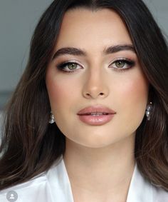 a woman with long hair wearing white shirt and earrings