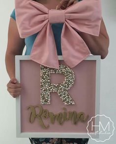 a woman holding up a sign with the letter r in it's center and a bow on her head