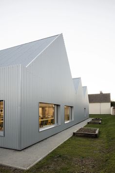 the exterior of a building with several windows and benches in front of it on a grassy area