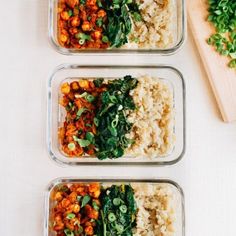 three glass containers filled with rice and vegetables next to a cutting board on top of a table