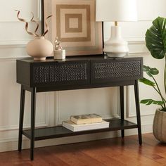 a black console table with two vases and a lamp